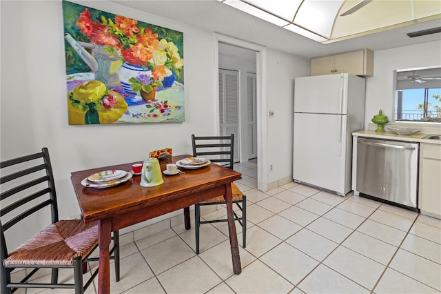 kitchen with visible vents, stainless steel dishwasher, freestanding refrigerator, light tile patterned flooring, and light countertops