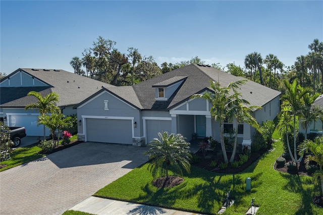 5621 Badini Way, Palmetto, FL 34221 - view of front of house with stucco siding, a garage, decorative driveway, a front lawn, and roof with shingles