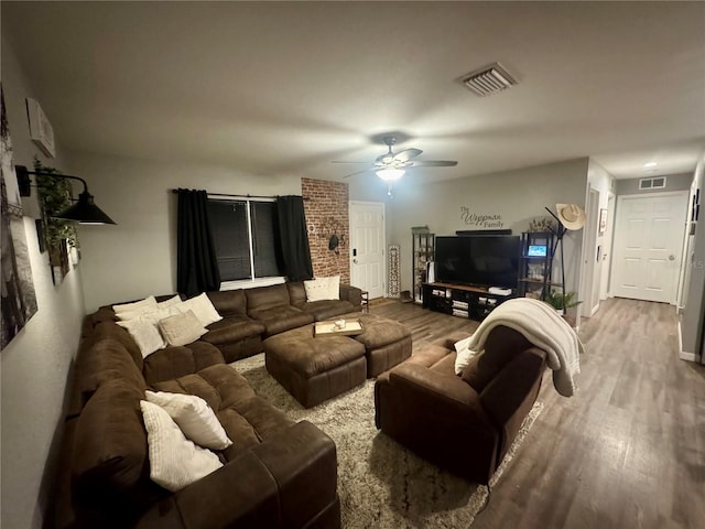 living area with visible vents, a ceiling fan, and wood finished floors