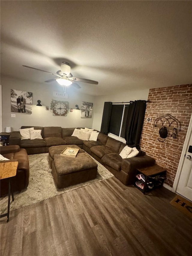 living area with brick wall, a textured ceiling, ceiling fan, and wood finished floors