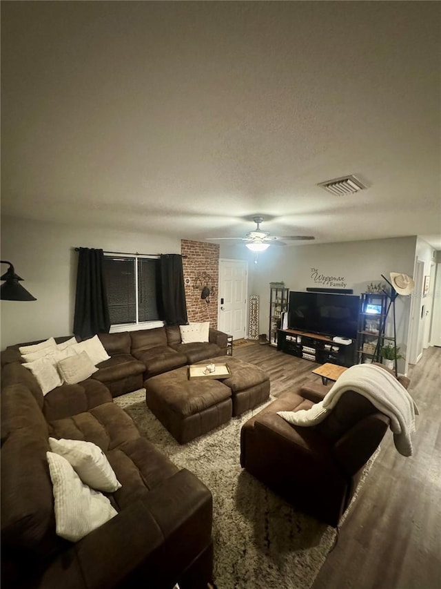 living room featuring visible vents, wood finished floors, and a ceiling fan