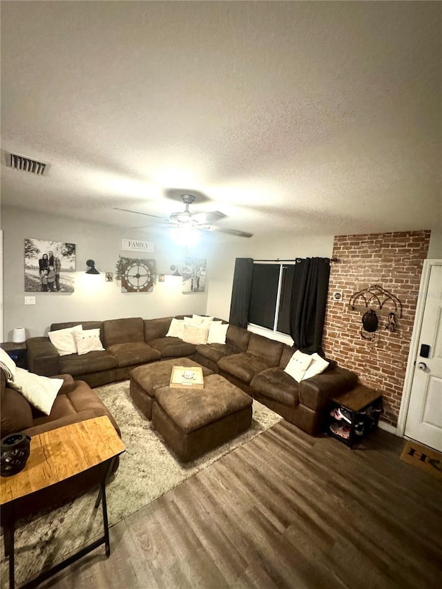 living room featuring a textured ceiling, wood finished floors, visible vents, and ceiling fan