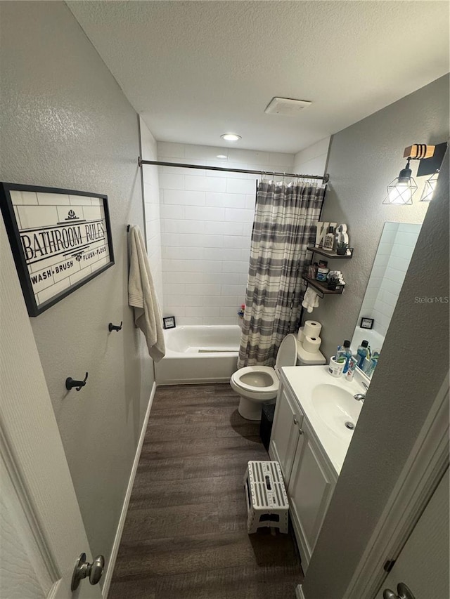 full bath featuring toilet, a textured ceiling, wood finished floors, vanity, and a textured wall