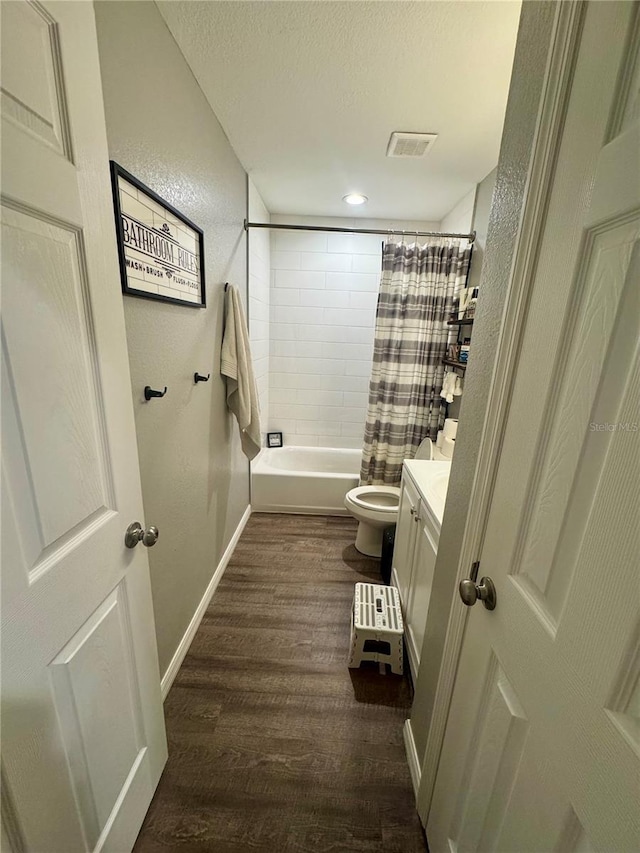 full bath featuring vanity, wood finished floors, visible vents, baseboards, and a textured ceiling