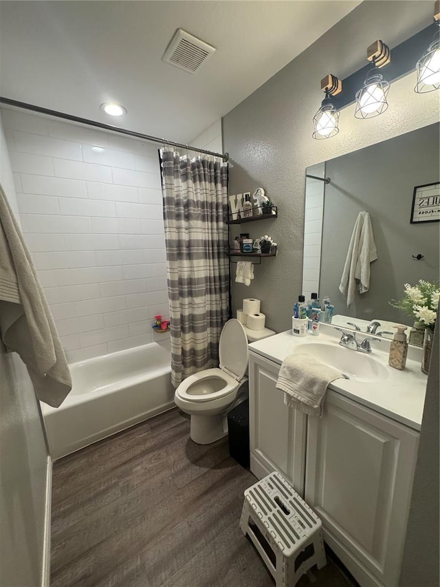 bathroom featuring vanity, wood finished floors, visible vents, shower / bath combo with shower curtain, and toilet