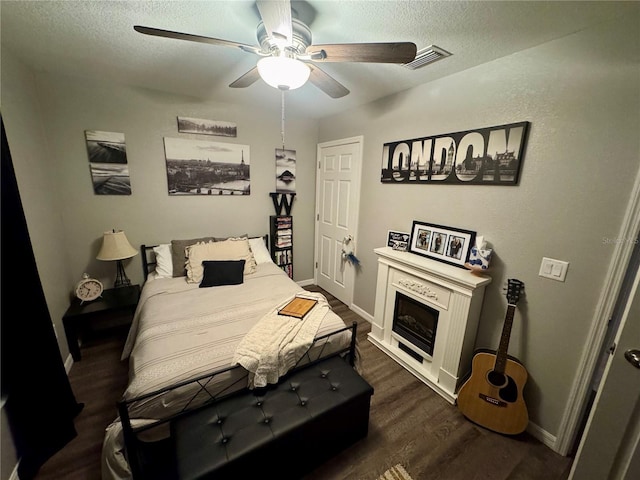 bedroom featuring visible vents, dark wood-type flooring, ceiling fan, baseboards, and a textured ceiling