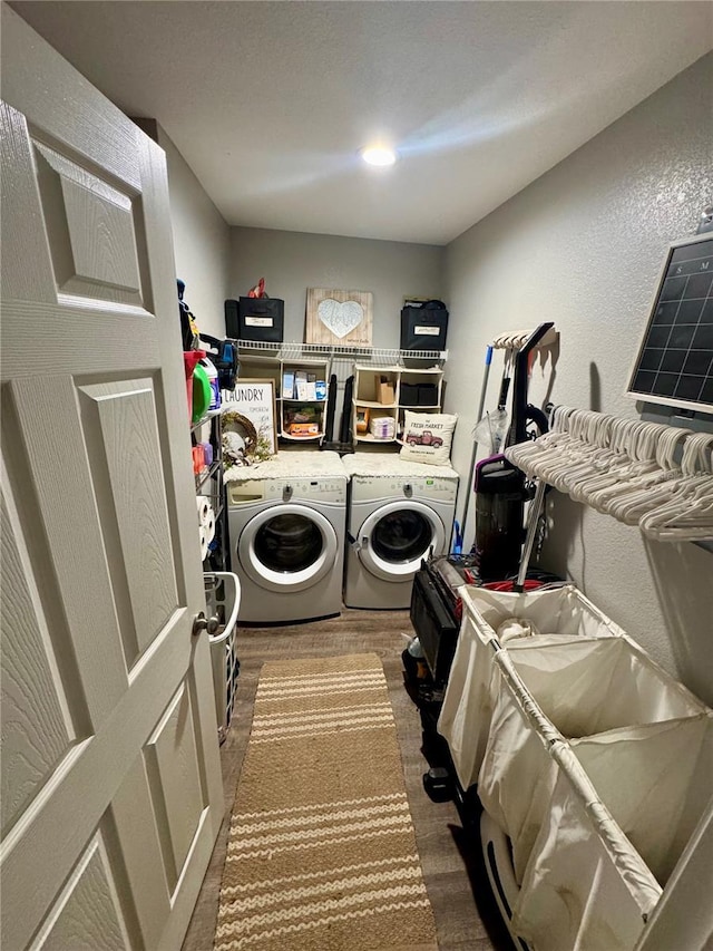 laundry area with laundry area, wood finished floors, a textured wall, and separate washer and dryer