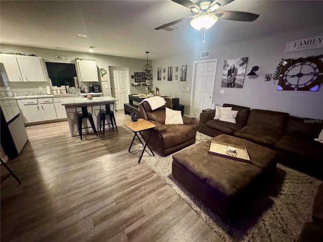 living area with visible vents, ceiling fan, and wood finished floors