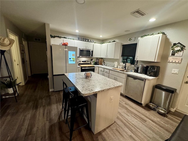 kitchen with visible vents, a center island, stainless steel appliances, a breakfast bar area, and dark wood-style flooring