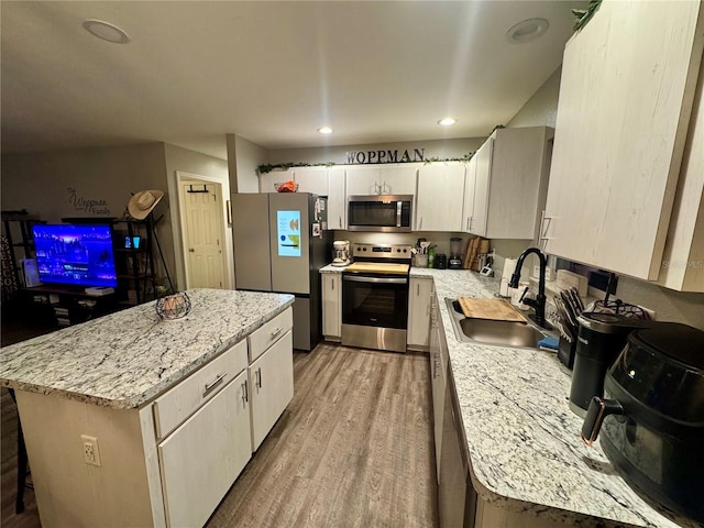 kitchen with light wood-style flooring, recessed lighting, a sink, stainless steel appliances, and a center island