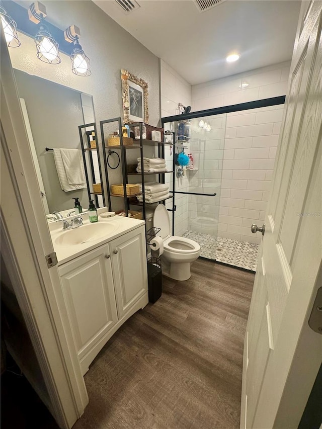 full bathroom featuring vanity, wood finished floors, visible vents, a stall shower, and toilet