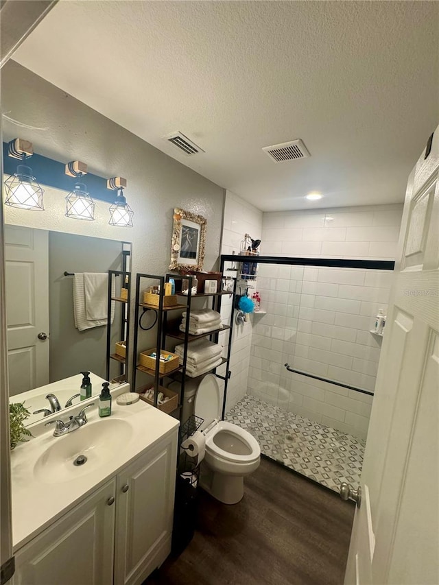 full bathroom featuring visible vents, a shower stall, a textured ceiling, and wood finished floors