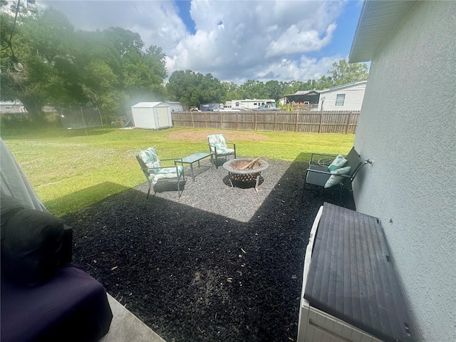 view of yard with a storage unit, a fire pit, an outbuilding, and a fenced backyard