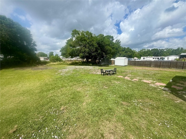 view of yard featuring a storage unit, an outbuilding, and fence