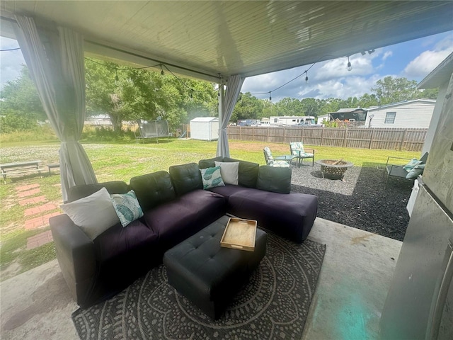 view of patio featuring an outbuilding, a storage shed, an outdoor living space with a fire pit, and a fenced backyard