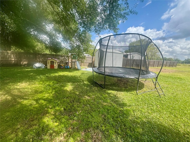 view of yard featuring a playground, a trampoline, and a fenced backyard