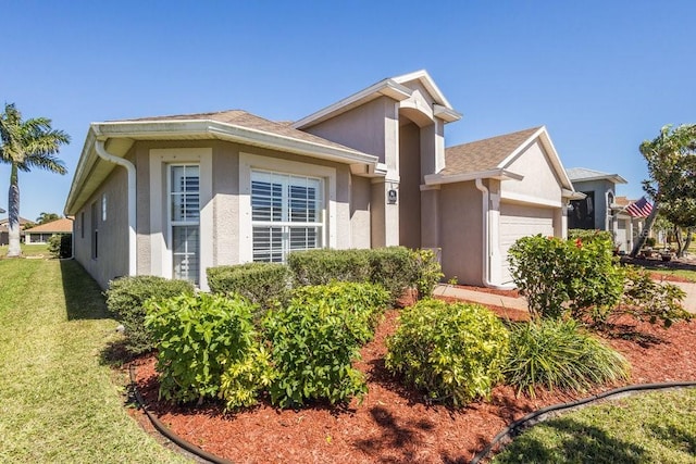 view of front of house with stucco siding, a front yard, and a garage