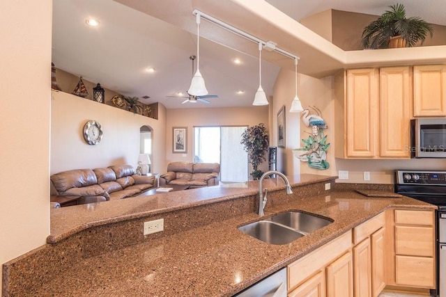 kitchen featuring light brown cabinets, open floor plan, dark stone countertops, appliances with stainless steel finishes, and a sink