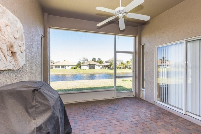 unfurnished sunroom with a water view and a ceiling fan