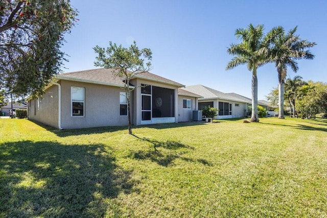 back of property with stucco siding, a lawn, and a sunroom