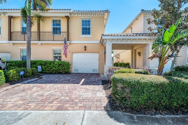 view of front facade featuring stucco siding, decorative driveway, a garage, and a tile roof