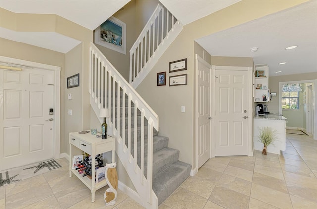 foyer entrance with stairs, recessed lighting, and baseboards