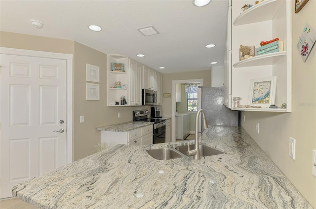 kitchen featuring open shelves, a sink, stainless steel appliances, white cabinets, and washer and dryer