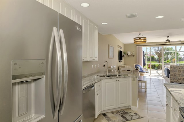 kitchen featuring a peninsula, light tile patterned flooring, a sink, ceiling fan, and stainless steel appliances