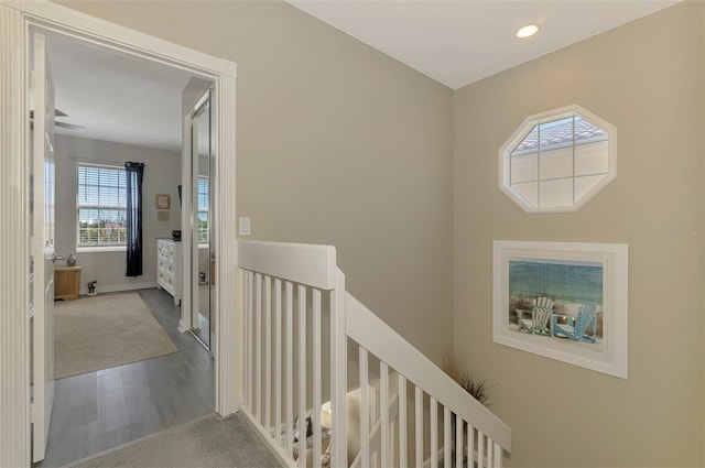 hallway featuring wood finished floors, recessed lighting, and an upstairs landing