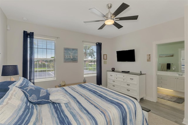 bedroom with connected bathroom, a ceiling fan, and light wood-style floors