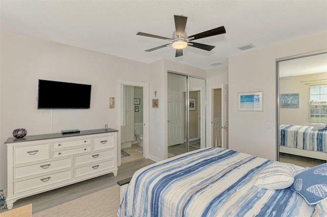 bedroom with visible vents, ensuite bathroom, wood finished floors, a closet, and ceiling fan