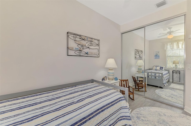 bedroom featuring a closet, visible vents, baseboards, and wood finished floors