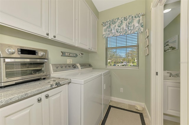 washroom with washing machine and dryer, baseboards, and a sink