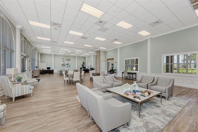 living area with visible vents, light wood-style flooring, decorative columns, crown molding, and a decorative wall