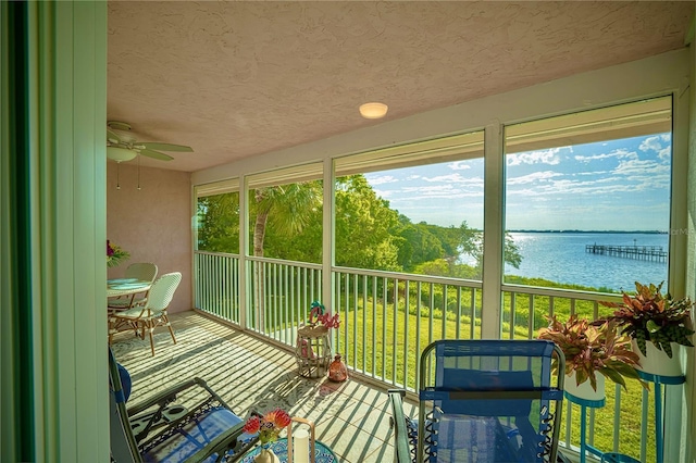 sunroom with a water view and ceiling fan