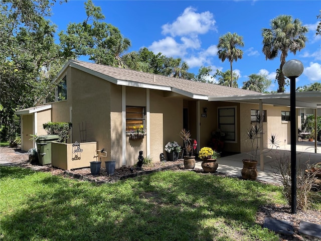 5013 Village Gardens Dr Unit 34, Sarasota, FL 34234 - view of front of property featuring a front yard, stucco siding, a patio area, and a shingled roof