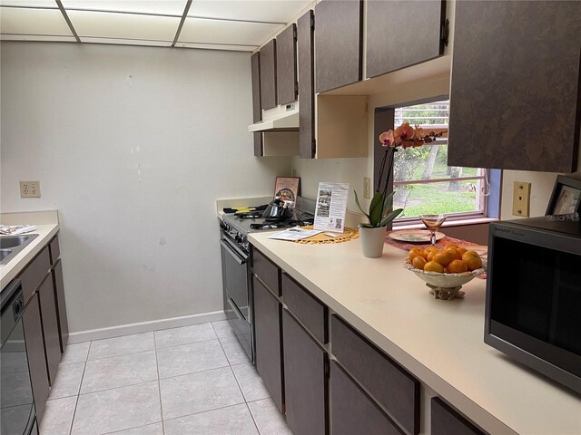 5013 Village Gardens Dr Unit 34, Sarasota, FL 34234 - kitchen with black appliances, under cabinet range hood, light countertops, light tile patterned floors, and dark brown cabinets