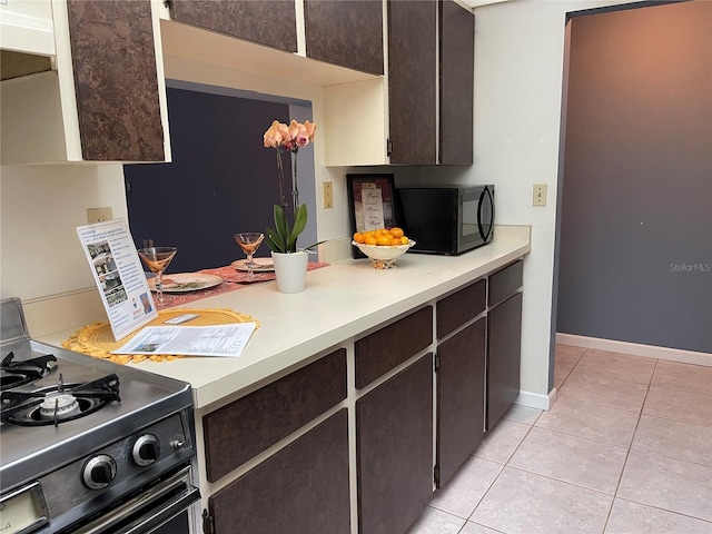 5013 Village Gardens Dr Unit 34, Sarasota, FL 34234 - kitchen featuring black appliances, dark brown cabinetry, light tile patterned floors, and light countertops
