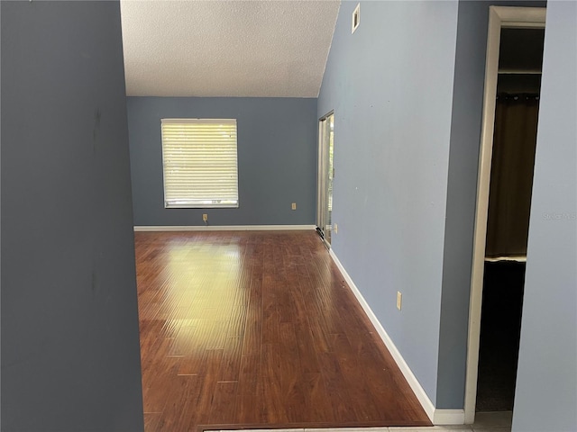 5013 Village Gardens Dr Unit 34, Sarasota, FL 34234 - spare room featuring wood finished floors, a textured ceiling, and vaulted ceiling