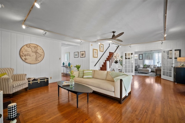 living room with stairs, rail lighting, wood finished floors, and a ceiling fan