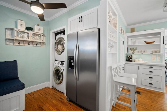 kitchen featuring open shelves, stainless steel fridge, stacked washer and dryer, and wood finished floors