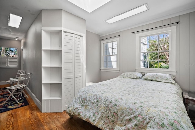 bedroom with a skylight, wood finished floors, and a closet