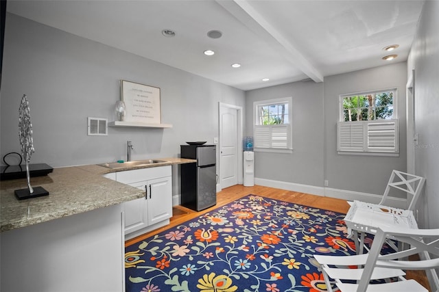 kitchen featuring baseboards, visible vents, beam ceiling, a sink, and light wood-type flooring