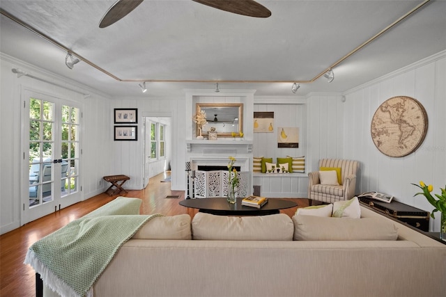 living area with a fireplace, crown molding, ceiling fan, and wood finished floors