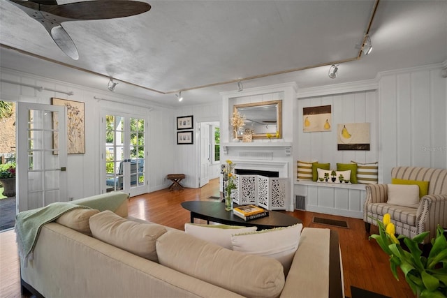 living room with wood finished floors, visible vents, a fireplace, track lighting, and crown molding