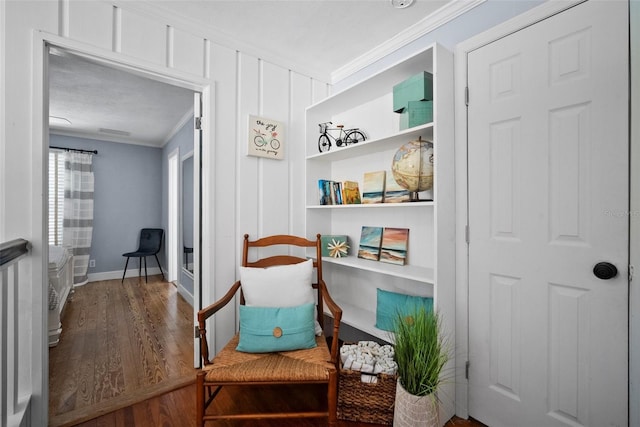 sitting room with crown molding, baseboards, and wood finished floors