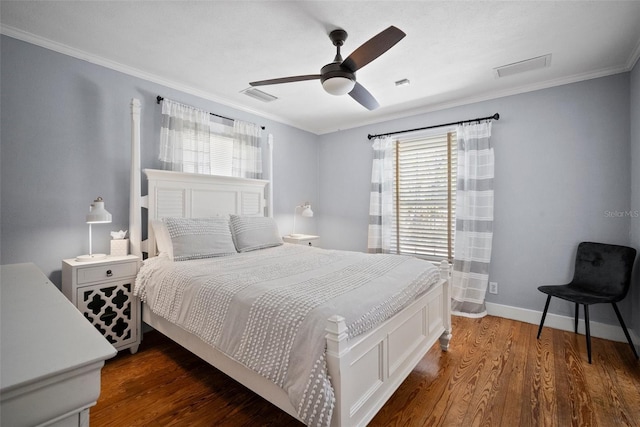 bedroom with visible vents, baseboards, wood finished floors, and crown molding