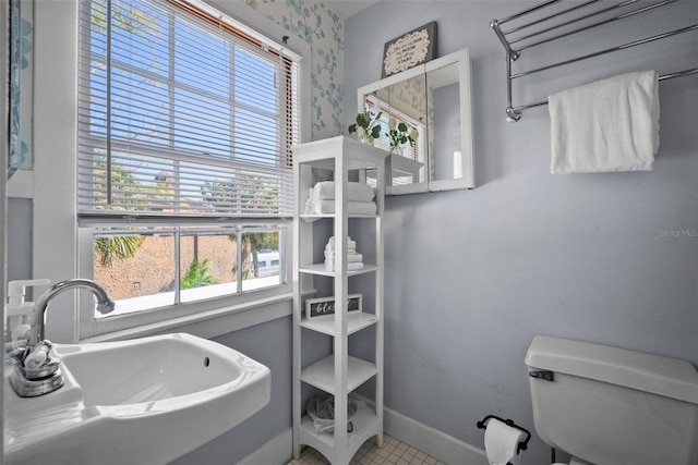 bathroom with toilet, baseboards, and a sink