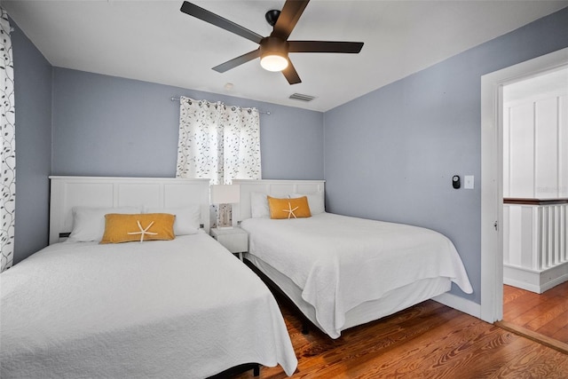 bedroom with baseboards, wood finished floors, visible vents, and ceiling fan