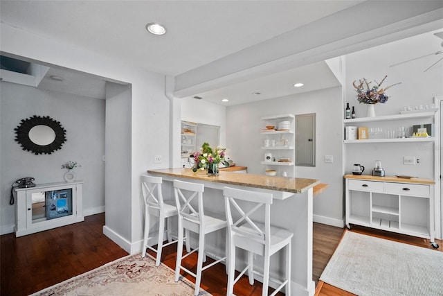 kitchen featuring open shelves, wood finished floors, recessed lighting, a breakfast bar area, and baseboards